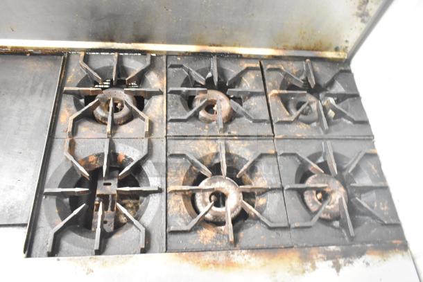 Commercial American Range gas 6-burner stove with griddle, two ovens, and backsplash, fair condition with visible wear.