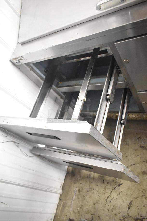 Delfield D4448N-18M-A22 sandwich prep table with 4 drawers, metal construction, visible wear, Delfield logo in view.