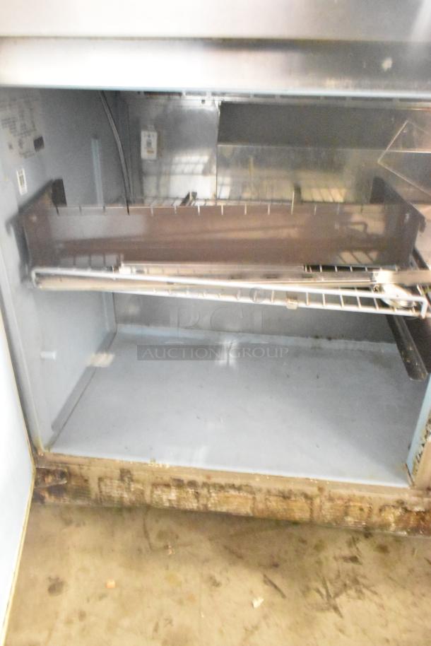 2017 Delfield 4460N-24M prep table, missing lid, 115V, 1 phase; interior shelf visible; moderate wear.