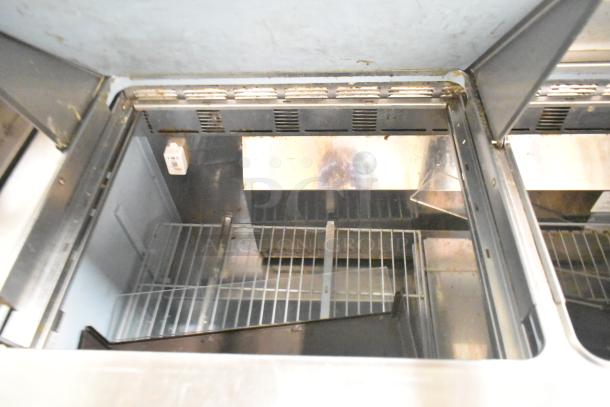 2017 Delfield 4460N-24M prep table, missing lid, interior view. Stainless steel, grid shelves, 115V, 1 phase.