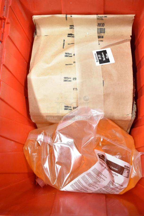 Red poly bin containing a brown paper bag and clear bags with text. Includes napkins, cups, utensils, 13 times your bid.