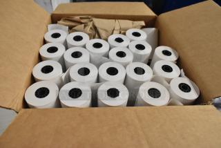 Box of white receipt paper rolls, new condition, multiple rolls neatly stacked in an open cardboard box, ready for use.