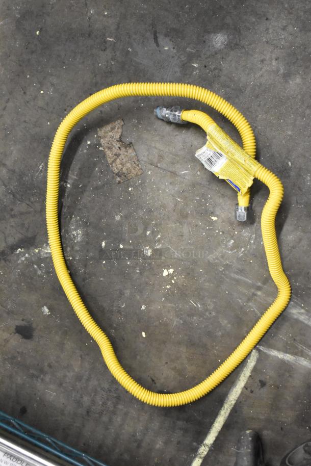 Yellow gas hose, new condition, with attached label showing barcode and safety warnings on industrial floor.