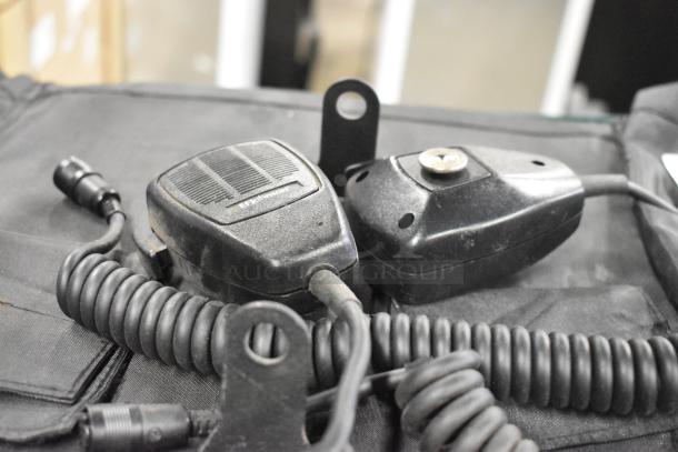 Lot of various items including microphones and a hanging holder on a black surface. Microphones have coiled cables.