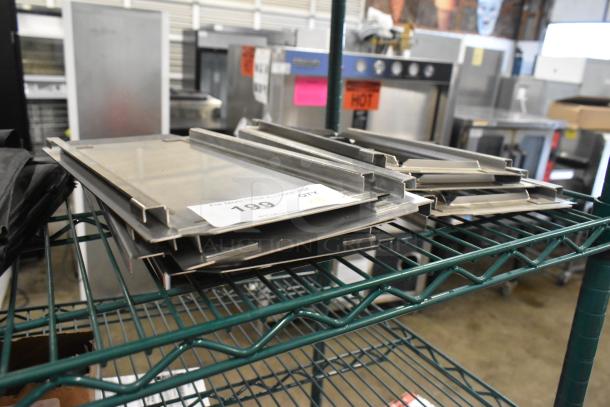Eight metal pan lids on a rack; four solid, four frame design. Auction tag visible, marked "199," indicating bid details.