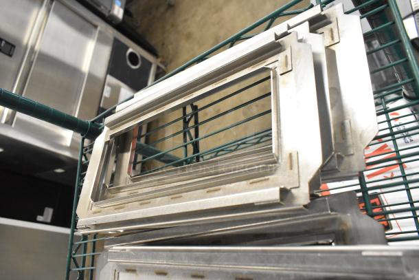 8 metal pan lids, including 4 solid and 4 frame designs, stacked on a green metal shelf; slightly used condition.