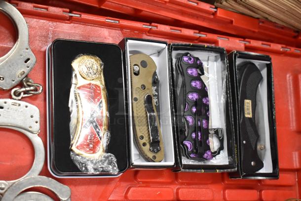 Collection of 25 items including handcuffs, various pocket knives with unique designs, and brass knuckles in original packaging.