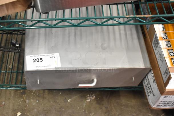 Stainless steel metal box with pull handle, slight wear, auction tag "#205" visible, resting on metal shelf.