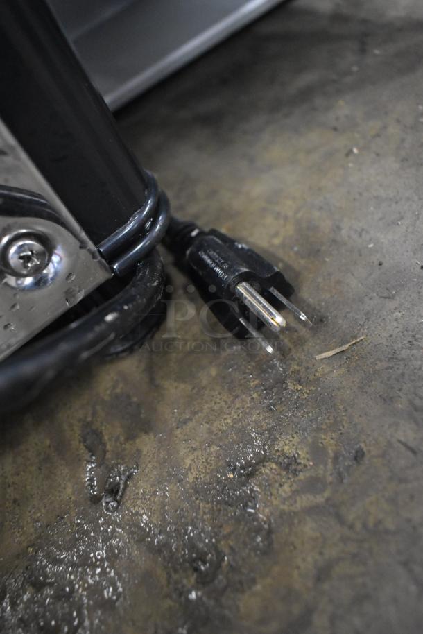 Close-up of 2024 Carnival King 382RBD3G1 beverage dispenser power cord and plug on wet concrete floor.