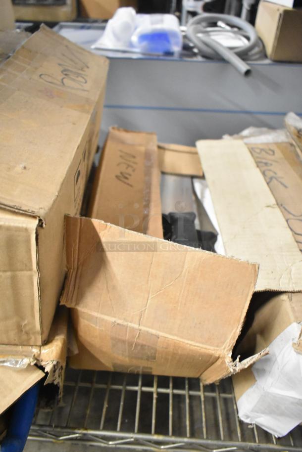 Cardboard boxes containing 80 sharpened stainless steel knives, including a chef knife, on a metal shelf. Box labeled "NEW".