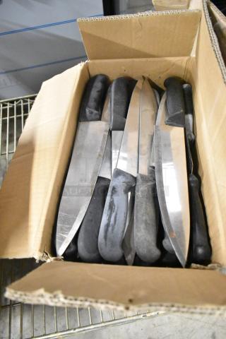 Box of 100 sharpened stainless steel knives, including serrated bread and chef knives. Black handles. Good condition.