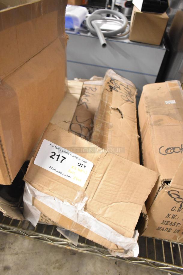 Boxes of 100 sharpened stainless steel knives, including serrated bread and chef knife. Labeled "217, Qty: x2 boxes, Approx. x100".