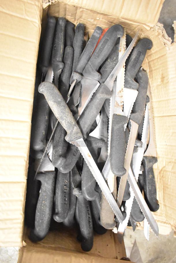 Box of 100 sharpened stainless steel knives including serrated bread and chef knives, with black handles, in used condition.