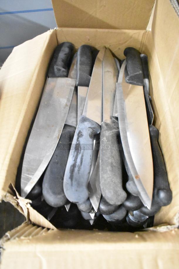 Box of 100 sharpened stainless steel knives, including serrated bread and chef knives. Black handles, bulk condition.