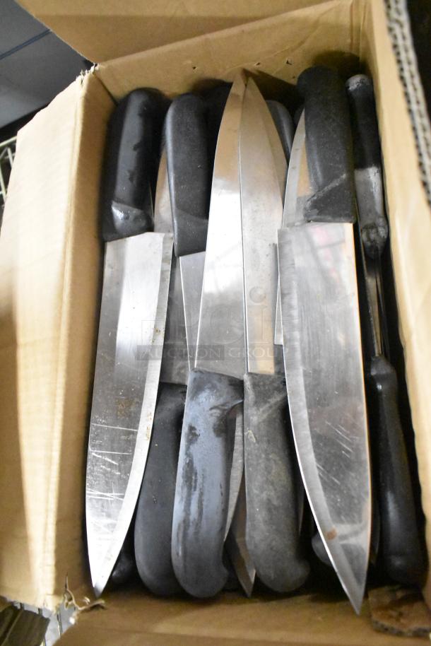 Box of 100 sharpened stainless steel knives, including serrated bread and chef knives, with black handles.