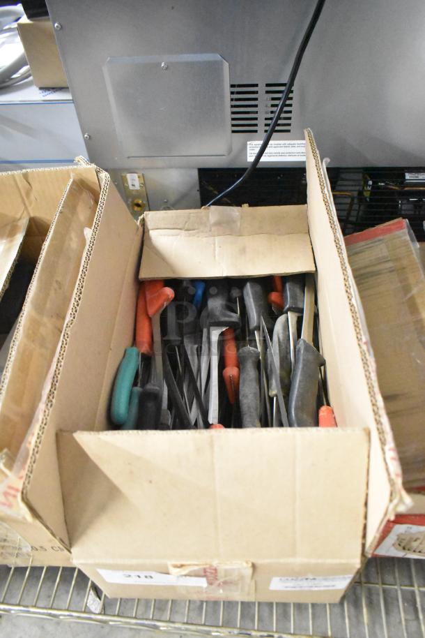 Box of 180 sharpened stainless steel knives, including chef, filet, and poultry knives, with assorted handle colors.