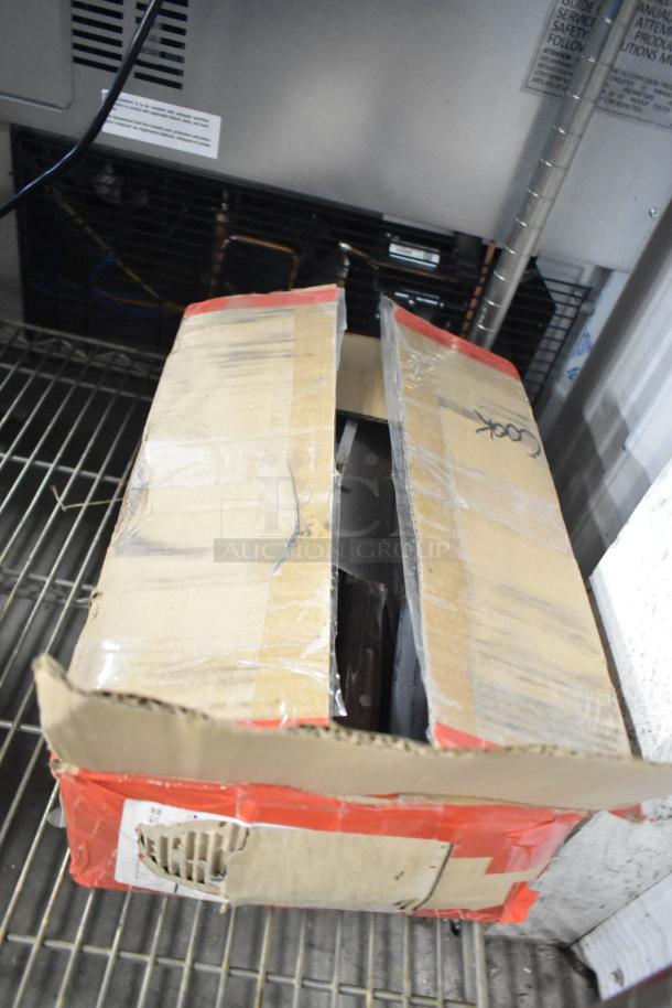 Open cardboard box containing 180 sharpened stainless steel knives. Includes chef, filet, and poultry knives. Box shows signs of wear.