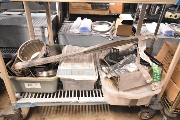 Auction lot with brew baskets, drip trays, and assorted metal items in bins and bags, visible label on bin marked "224."