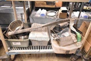 Auction lot with brew baskets, drip trays, and assorted metal items in bins and bags, visible label on bin marked "224."