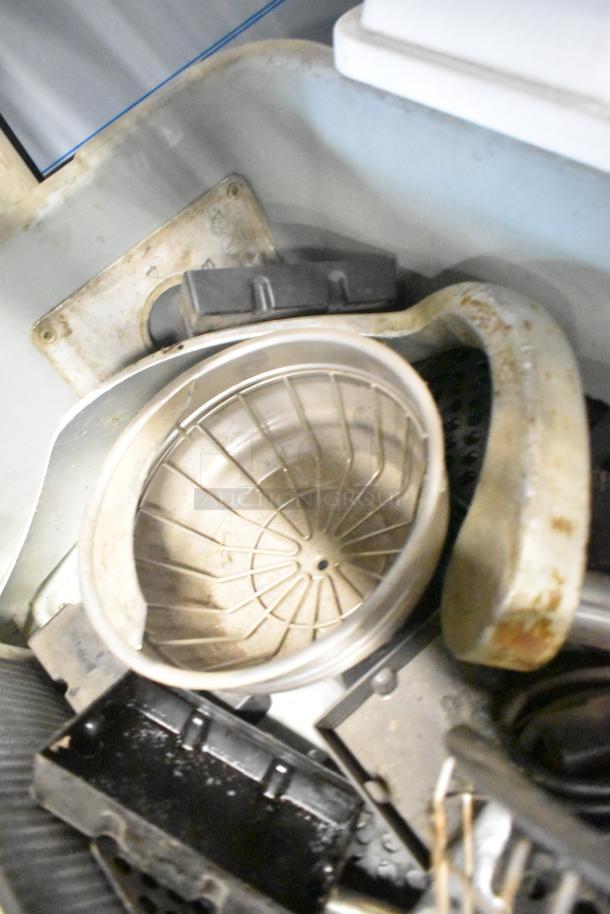Tiered lot including metal brew baskets and plastic drip trays, various used items, showing wear, suitable for parts or repair.