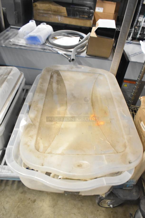 Tiered lot of miscellaneous items including brew baskets and drip trays, stored in a slightly dusty, transparent plastic bin.