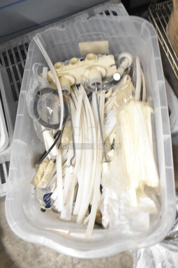 Plastic bin containing various items including brew baskets, drip trays, plastic tubing, and fittings. Items appear used.