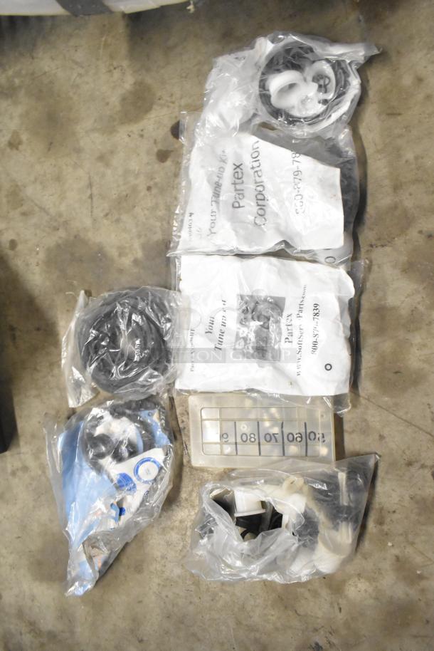 Tiered lot of assorted items including brew baskets, drip trays, and miscellaneous parts in plastic bags. Markings include "Partex Corporation." Items appear new and sealed, ideal for coffee equipment maintenance.