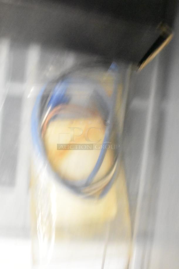 Blurry image of various items; includes cables and unknown objects. Exact details unclear due to image quality.