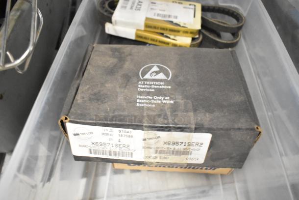 Box labeled "X69571SER2" containing a static-sensitive device in a lot with belts and various items. Condition appears used.