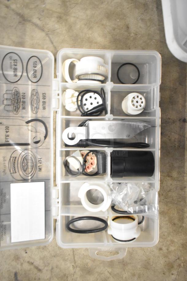 Clear plastic organizer containing assorted brew baskets, drip trays, and coffee machine components. Various sizes and conditions.