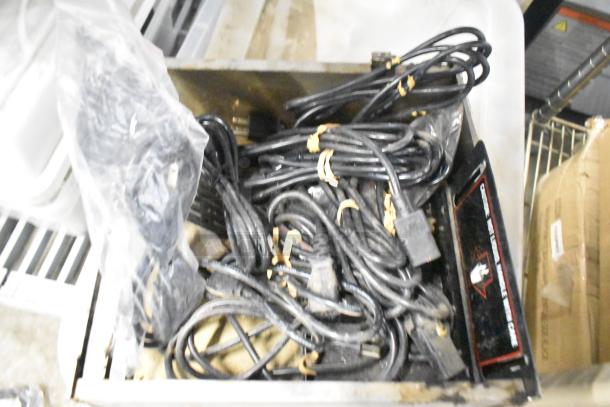 Various items in a bin, including black cables, brew baskets, and drip trays. Cables are tied and appear used.
