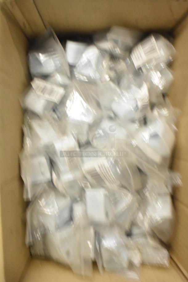Box of assorted items including mixing cup collars and fluorescent sockets in sealed bags, visible barcodes on packaging.