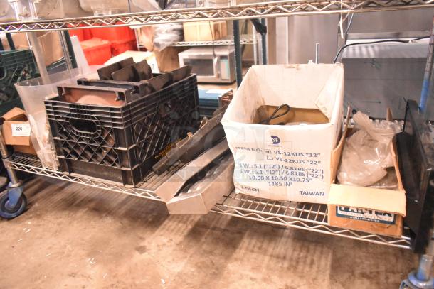 Tiered metal shelf with assorted items including range grates, slushie machine hopper, Turbochef kickplates. Box labels visible.