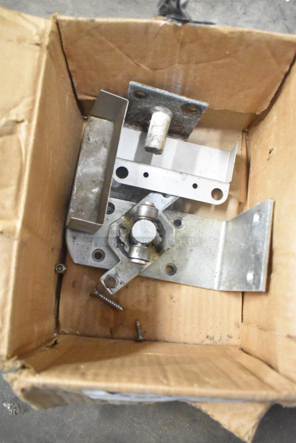 Cardboard box containing assorted metal parts, including range grates and a Turbochef kickplate, in used condition.