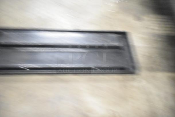 Blurry image possibly depicting a black Turbochef kickplate. Part of a tier lot with range grates and slushie machine hopper.