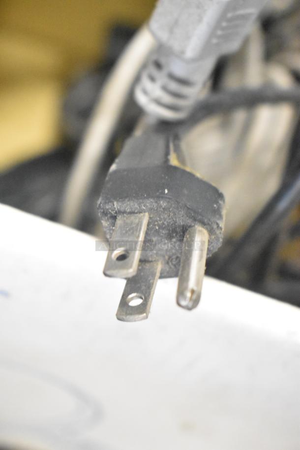 Close-up of a worn electrical plug with a black casing and two metal prongs, part of a mixed auction lot.