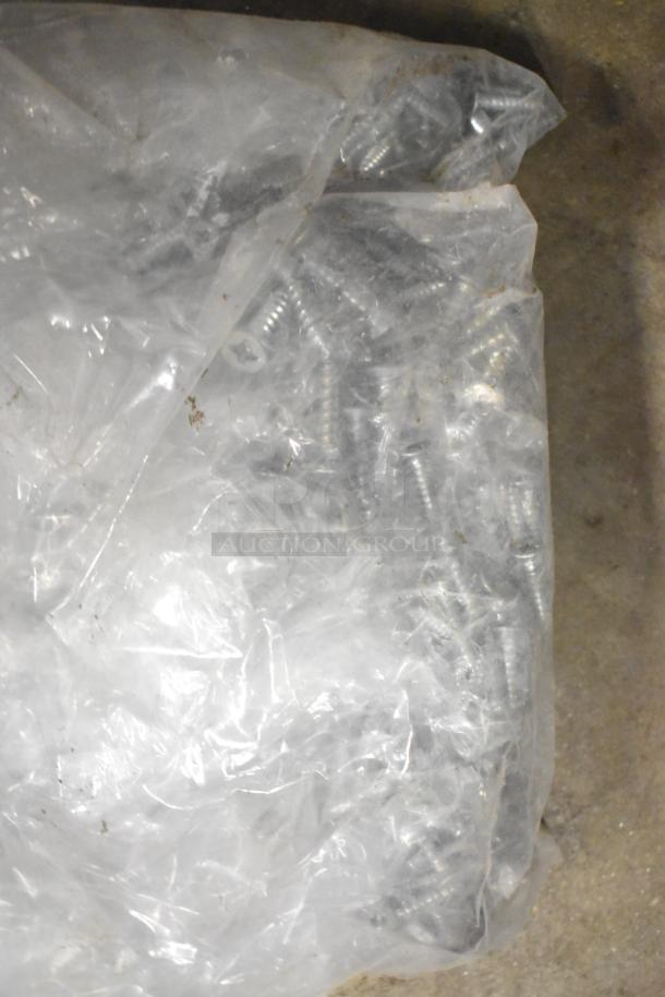 Bag of mixed metal screws, partially visible through clear plastic. Part of a tier lot including kitchen and appliance parts.