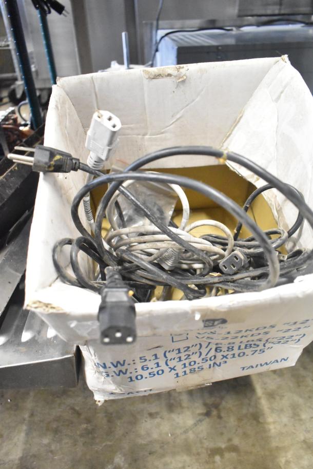 Box of assorted cables and plugs, visible wear, for various electronic items; includes packaging with dimensions and weight details.