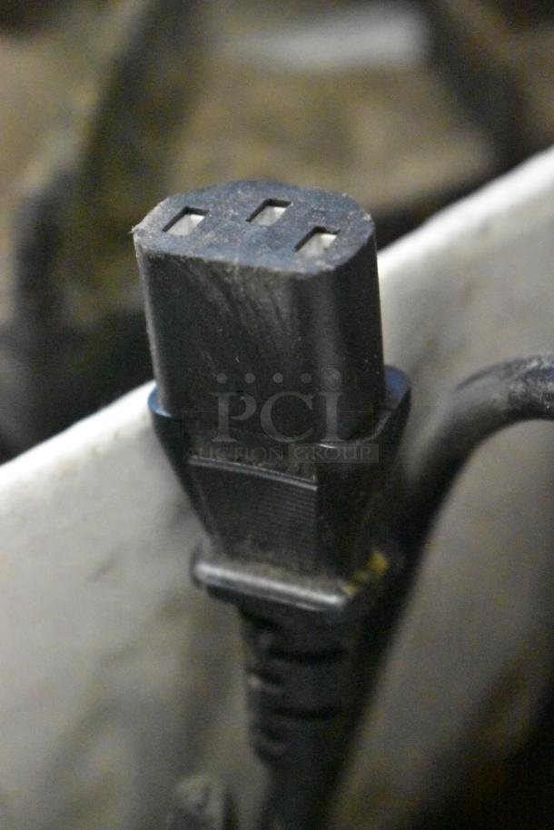 Close-up of a black power plug connector, part of a mixed lot including range grates, slushie machine hopper, and Turbochef kickplates.