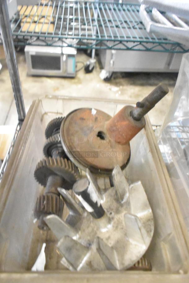 Auction lot of mixed items including rusted metal gears, grinder parts, and a pelican head grating blade in used condition.