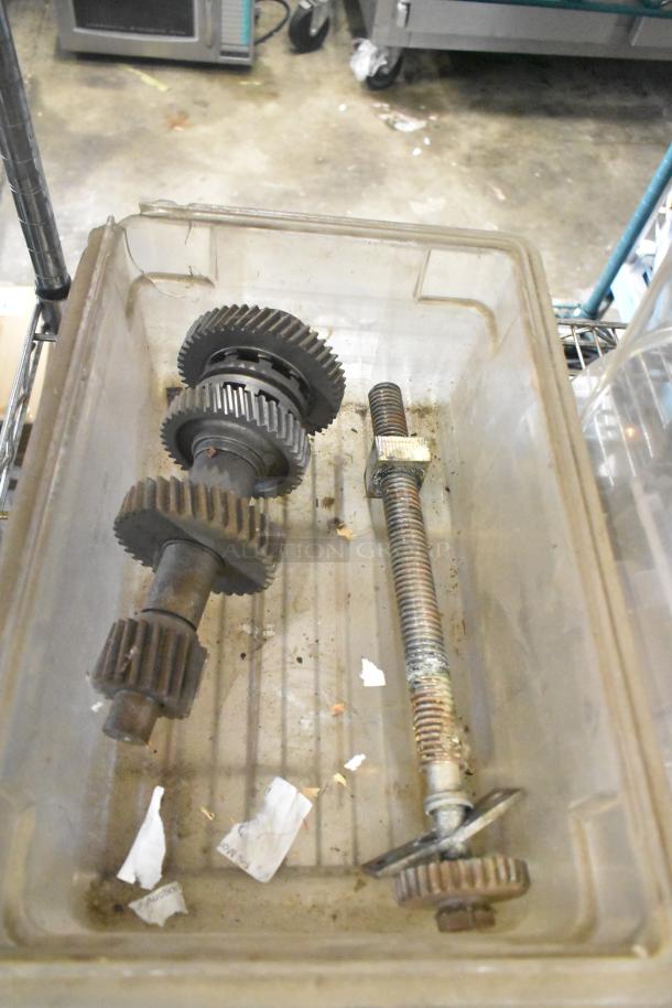 Plastic bin with metal gears and threaded rods, part of a tier lot including slushie machine hoppers and metal panels.