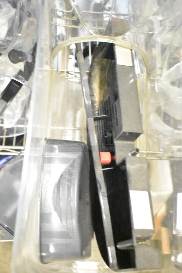 A collection of items including slushie machine hoppers, metal panels, a meat grinder tray, and a grating blade stacked in bins.