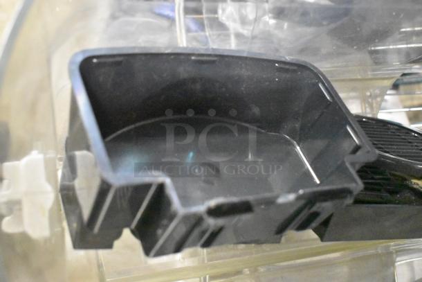 A black plastic tray, part of a mixed lot including slushie machine hoppers, metal panels, and a grating blade.