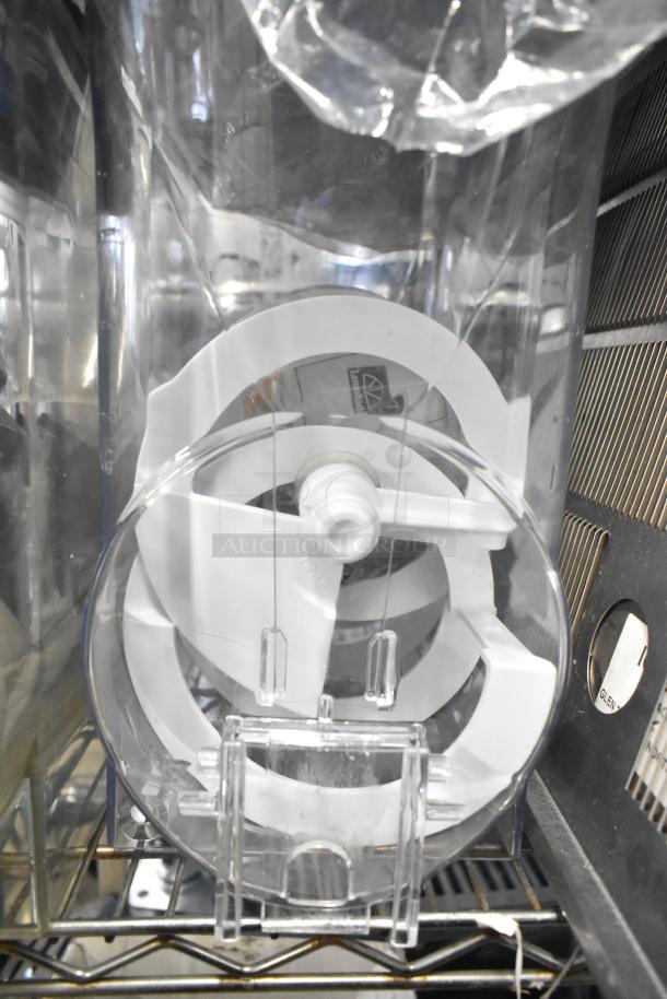 Clear plastic slushie machine hopper with visible internal paddles. Part of a lot including metal panels, meat grinder tray, and grating blade.