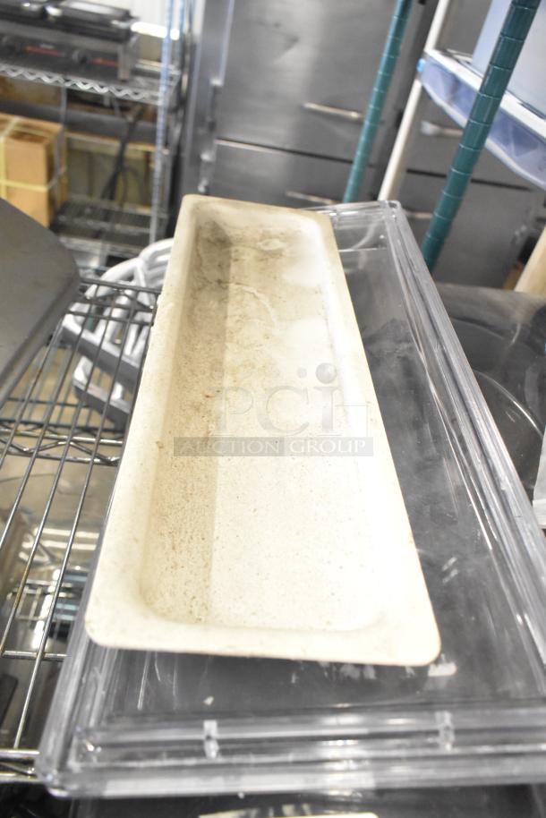 Various kitchen equipment, including a narrow, rectangular ice cream machine lid, shown on a metal shelf.