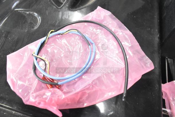 Various wires on pink plastic wrap, featuring black, blue, and yellow cables; part of a tier lot of mixed items.