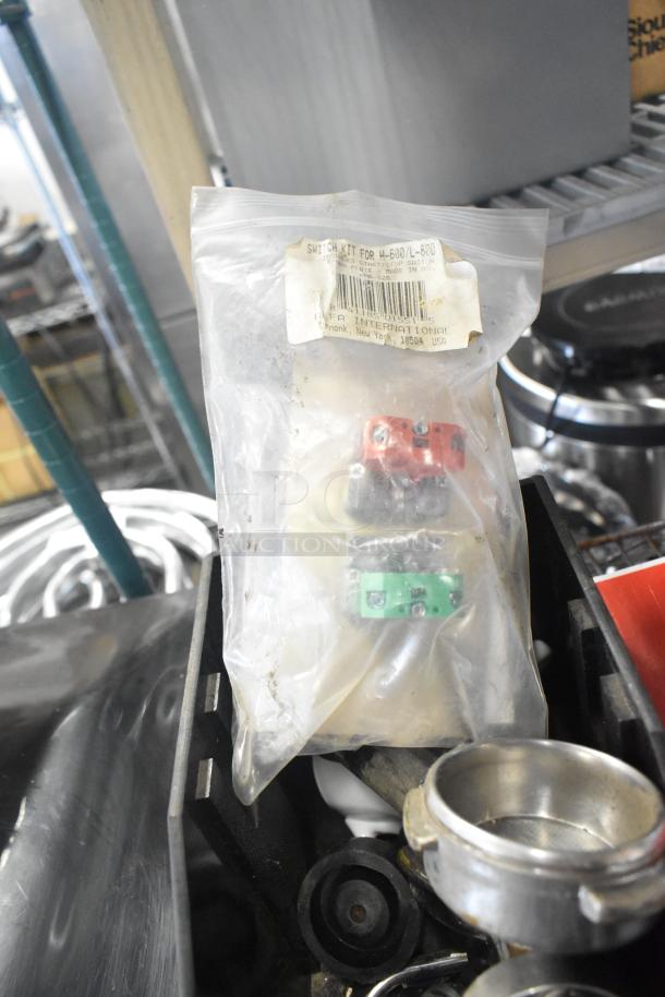Lot of assorted items including switch kit for H-600 in packaging, portafilters, and various machine parts. Tags visible.