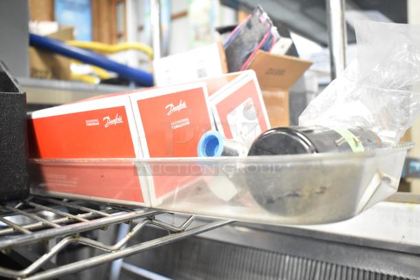 Assorted lot with Danfoss eliminator filter drier, Bunn dispenser spouts, ice cream machine lids, and more. Boxes and parts visible.