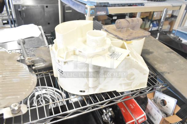 Alt text: "Auction lot with Pelican Head Blade, food processor grating blades, and meat slicer carriage on metal shelf."