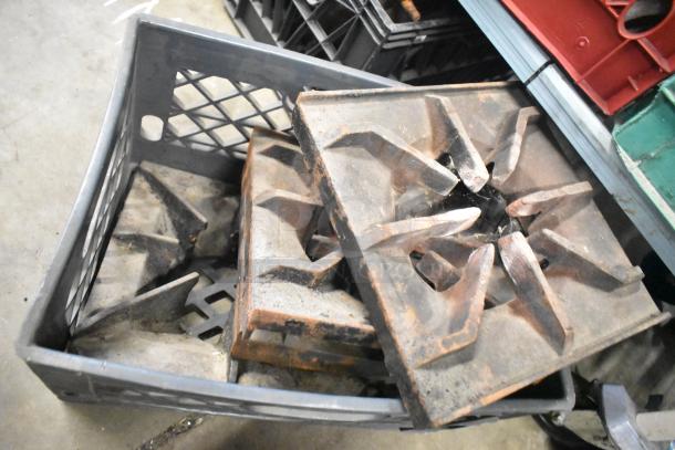 Nine used metal range grates in a crate, showing wear and rust, ideal for stoves or reclamation projects.